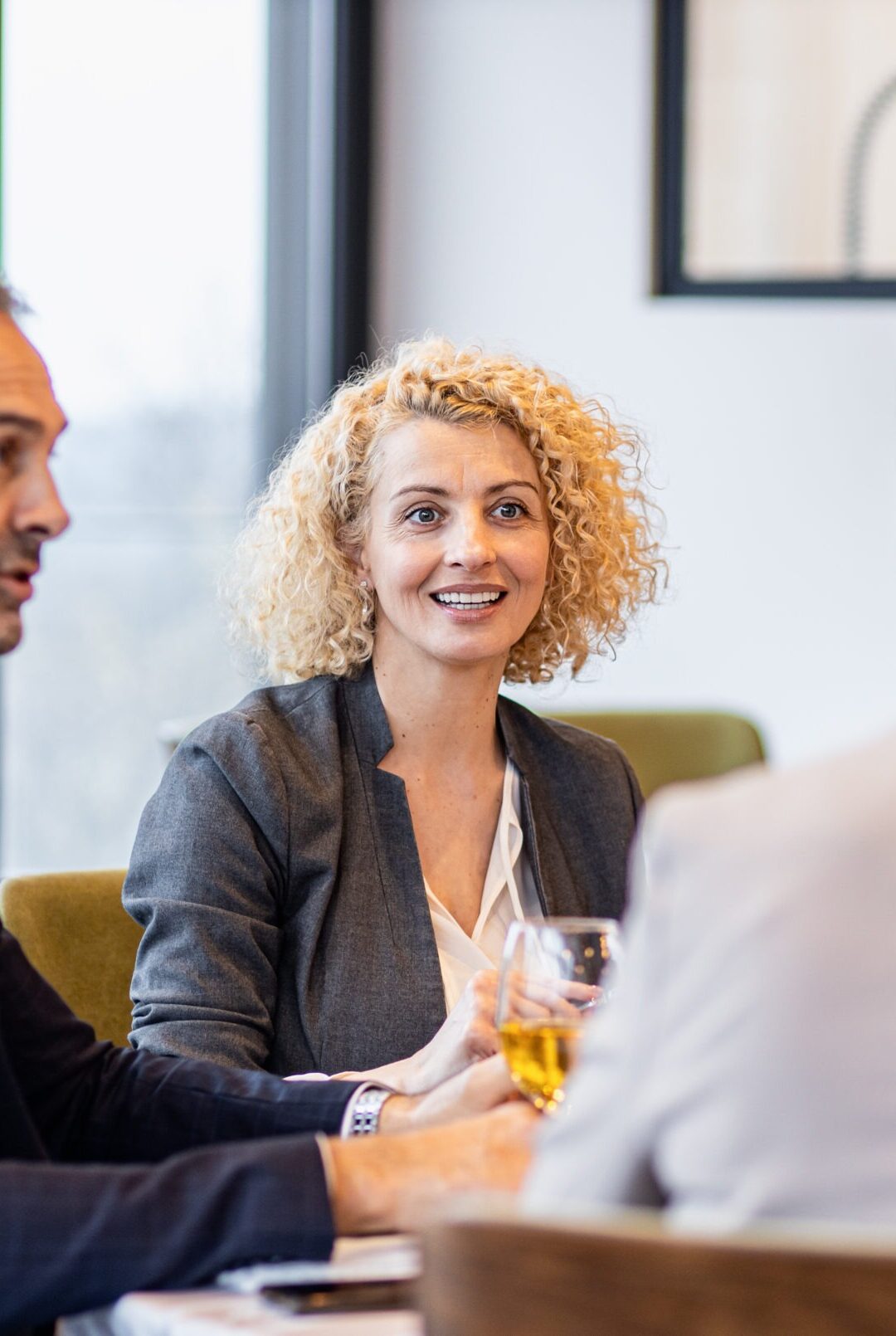 Portrait of businesswoman sitting with coworkers in restaurant during business lunch.